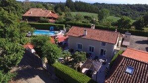 Une maison avec une piscine, entourée de verdure et située dans un paysage vallonné.