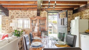 A dining area with a wooden table set for four, surrounded by stone walls and wooden beams. - House next door in Barcenaciones (Barcenaciones)