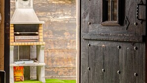 An outdoor dining area with a rustic wooden door, a grill, and a view of a well-maintained lawn. - House next door in Barcenaciones (Barcenaciones)