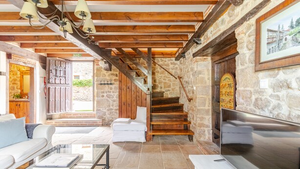 A spacious living area with a stone wall, a wooden staircase, and a fireplace. - House next door in Barcenaciones (Barcenaciones)
