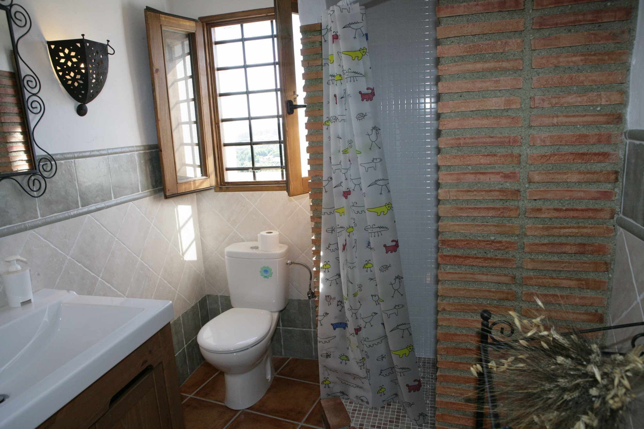 Une salle de bain avec un lavabo blanc, des toilettes et un rideau de douche à motifs animaliers.