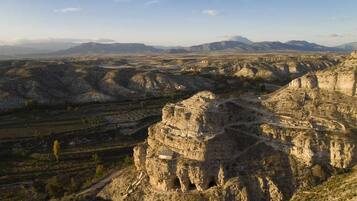 A rugged landscape with a prominent rock formation and terraced structures.