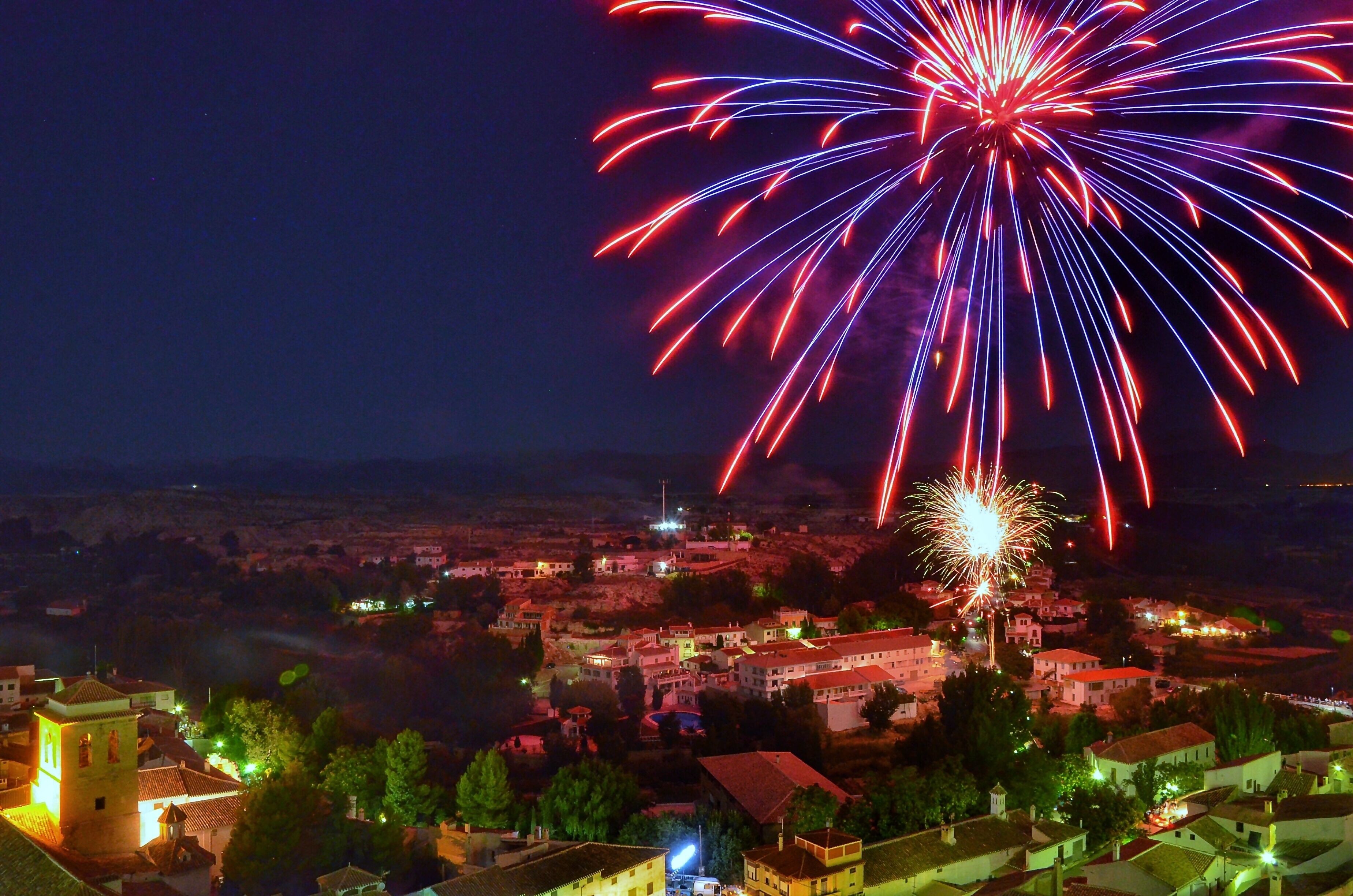 Un pueblo con una imponente torre de iglesia y una vista de fuegos artificiales en el cielo.