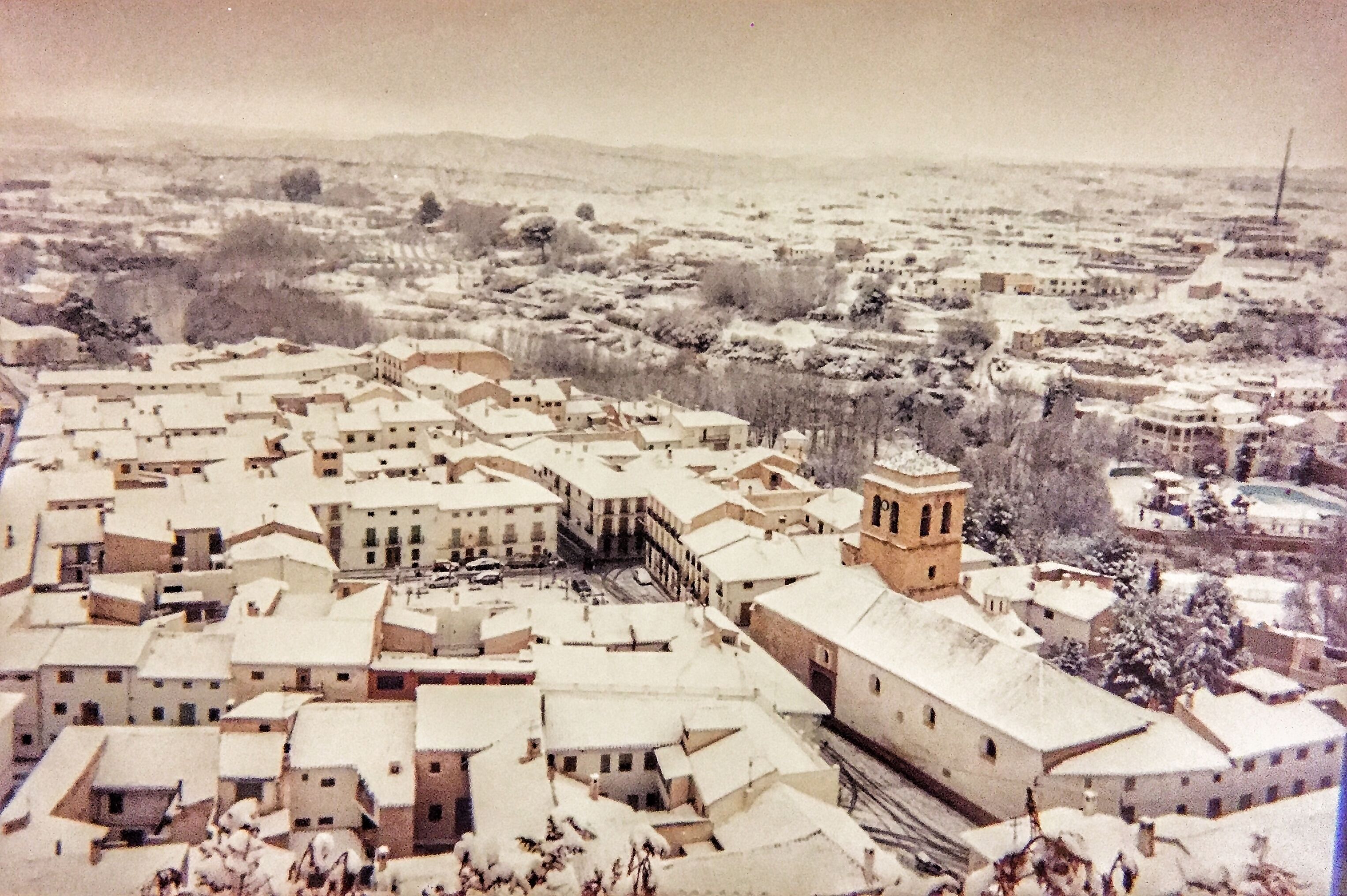 A snow-covered town with a prominent building featuring a tower.