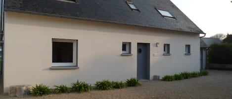 A single-story building with a sloped roof, a small porch, and a gravel driveway.
