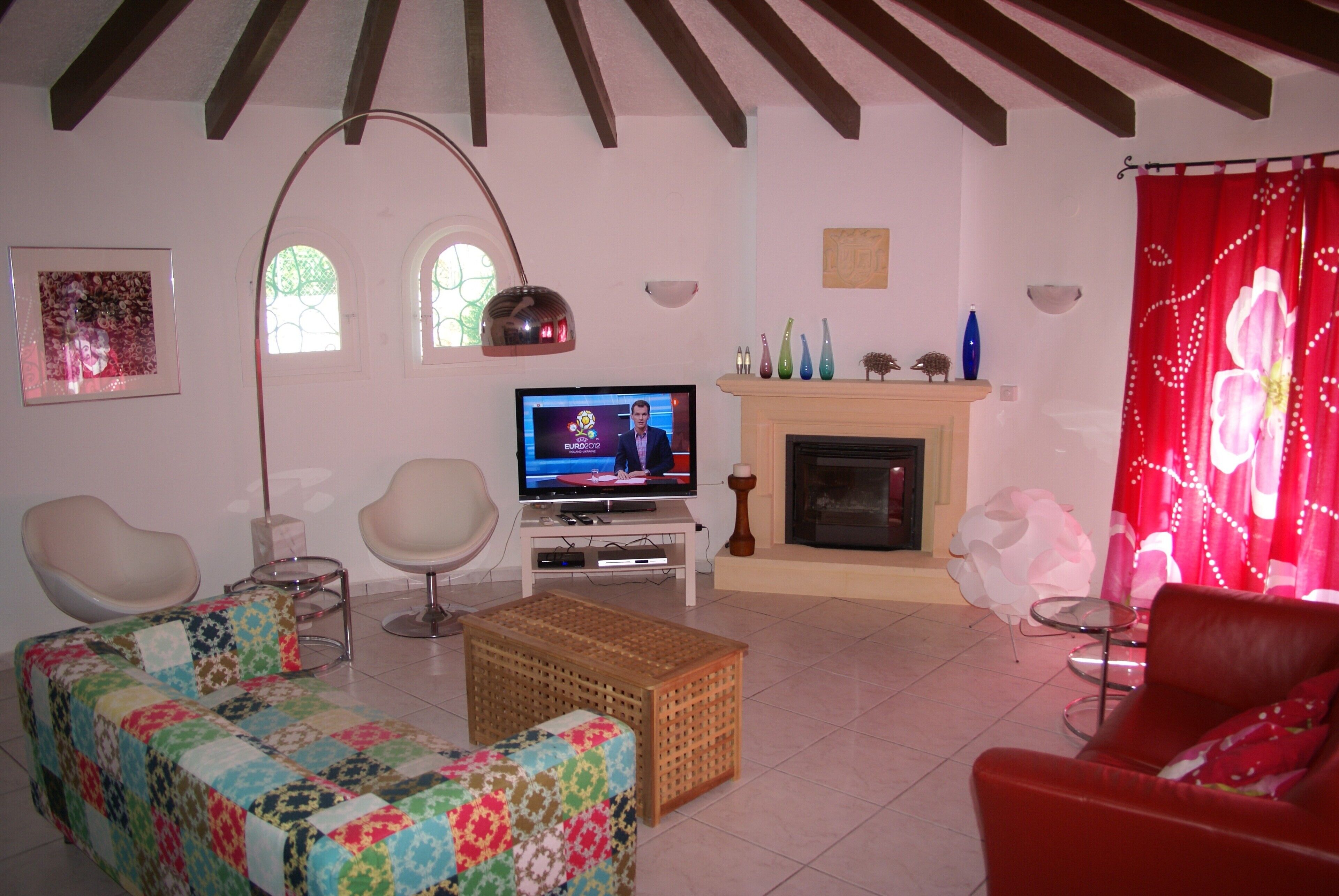A living room with a television, two chairs, a sofa, a fireplace, and a window with decorative glass.