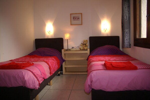 Un dormitorio con dos camas, cada una con cabecera y mesita de noche. Hay una lámpara en la mesita situada entre las camas.