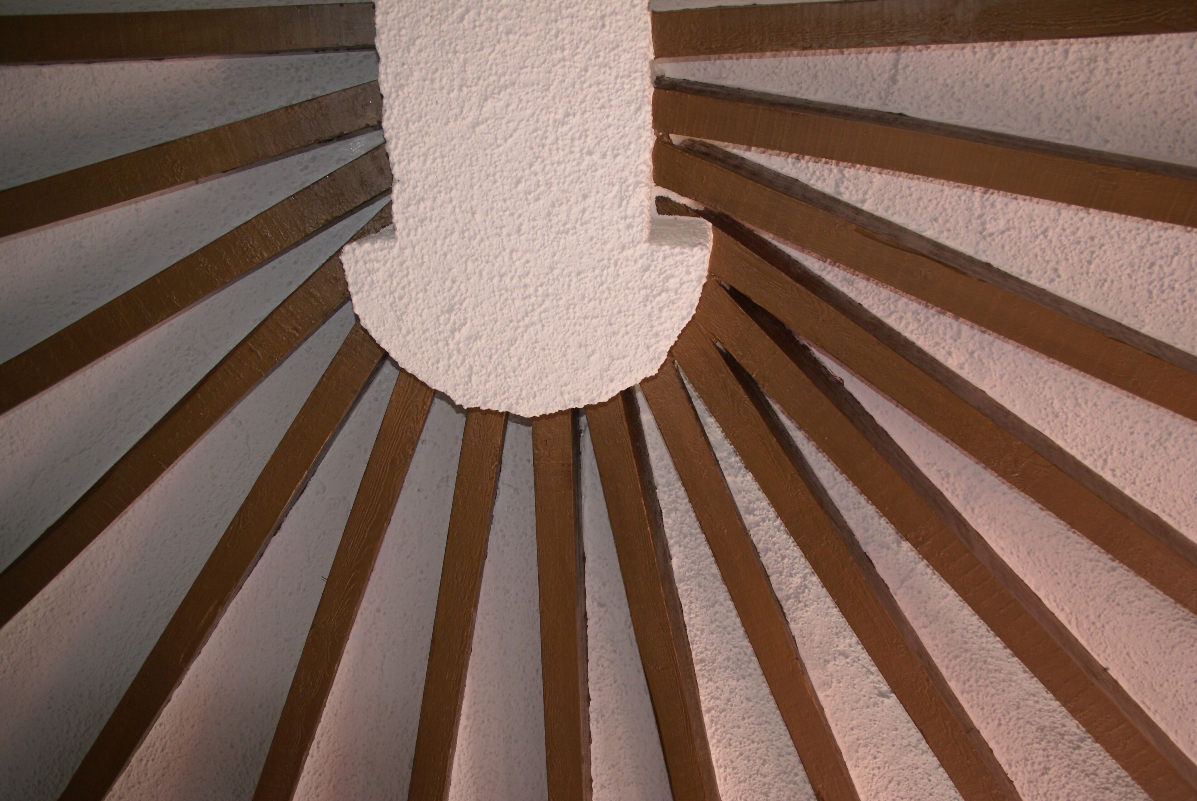 A spiral staircase with wooden steps and white walls.