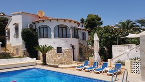 Un área de piscina con sillones de descanso y un muro de piedra.