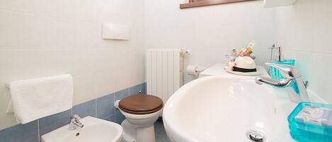 Une salle de bain comprenant des toilettes, un bidet, un lavabo et une baignoire.
