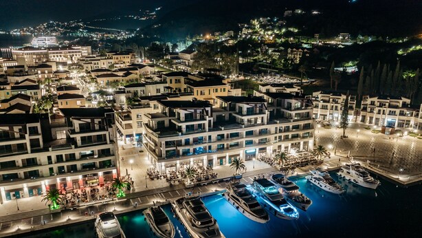 Een jachthaven met diverse jachten aanmeren, omringd door moderne gebouwen met balkons en terrassen.