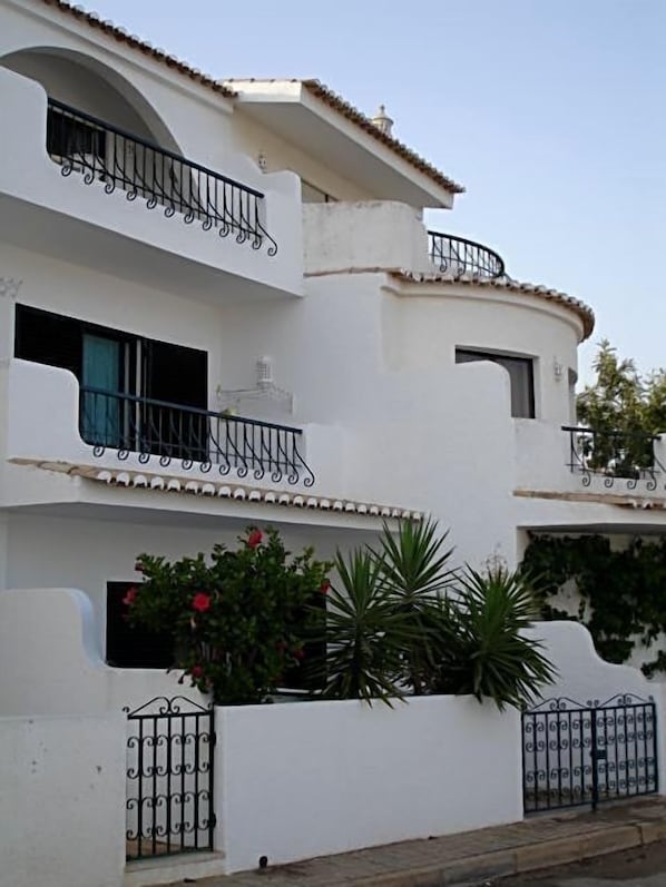 A multi-story building with balconies, white walls, and a tiled roof. - Apartment with stupendous ocean views, 50 meters from the beach (Luz)