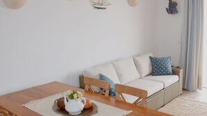 Zona pranzo con tavolo di legno, sedie e un boccale bianco su un sottopiattino.