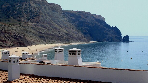 Una vista costiera con spiaggia, scogliere ed edifici bianchi con torri.