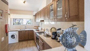 Una cucina moderna con mobili in legno, forno integrato, lavatrice e una scultura decorativa in metallo.