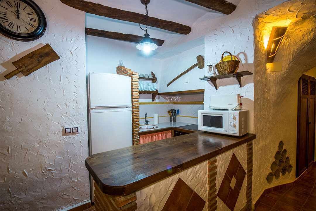 Una cocina rústica con encimera de madera, un refrigerador blanco, un microondas y una cesta colgante.