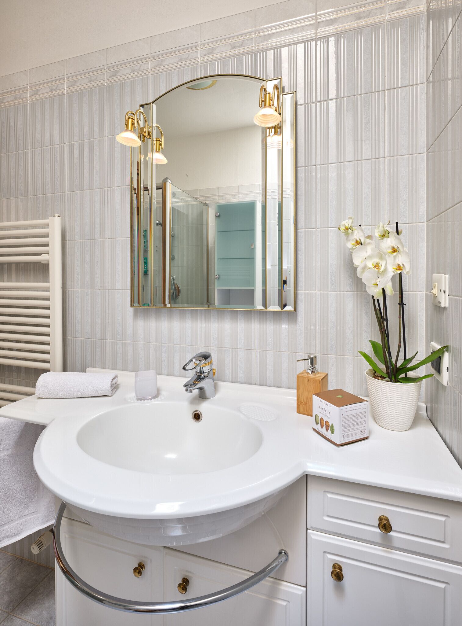 A bathroom with a large mirror, white sink, and a towel rack.