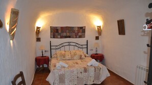 Ein gemütliches Schlafzimmer mit einem Bett, zwei Nachttischen, einem Sessel und einem gesteppten Kopfstück.