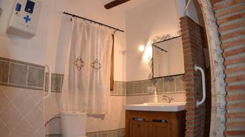 Une salle de bain équipée de toilettes, d’un bidet, d’un lavabo et d’un rideau de douche.