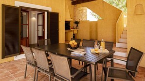 An outdoor dining area with a table set for six, surrounded by chairs, and a staircase leading to an upper level. - CAN NOVES - Detached, central and peaceful villa (Sant Francesc de Formentera)