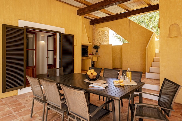 An outdoor dining area with a table set for six, surrounded by chairs, and a staircase leading to an upper level. - CAN NOVES - Detached, central and peaceful villa (Sant Francesc de Formentera)