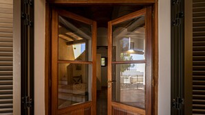 A wooden double door with glass panels, leading into a hallway with a tiled floor. - CAN NOVES - Detached, central and peaceful villa (Sant Francesc de Formentera)