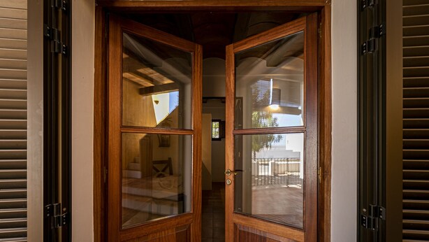 A wooden double door with glass panels, leading into a hallway with a tiled floor. - CAN NOVES - Detached, central and peaceful villa (Sant Francesc de Formentera)