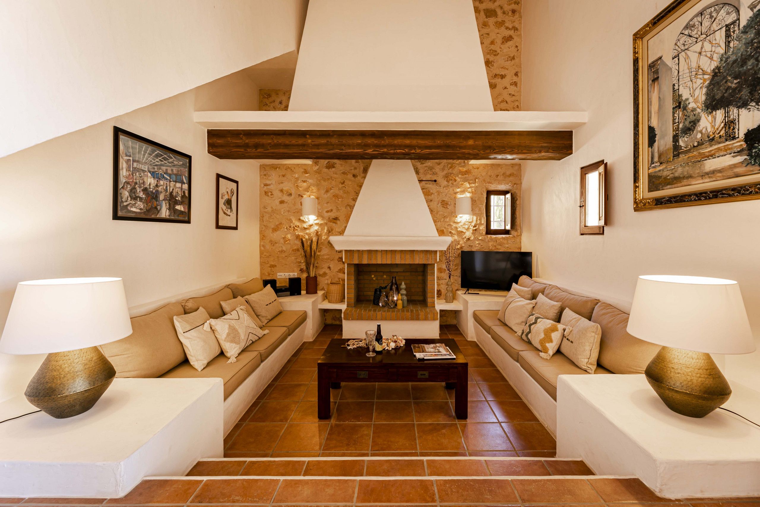 A living room with two sofas, a coffee table, a fireplace, and wall-mounted lamps.