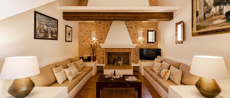 A living room with two sofas, a coffee table, a fireplace, and wall-mounted lamps.