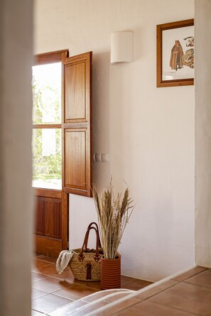 A room with a wooden door, a framed picture on the wall, and a woven basket with a plant.