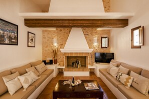 A living room with two sofas, a coffee table, a fireplace, and a television. - CAN NOVES - Villa 5 suites 9 & 31 (Sant Francesc de Formentera)