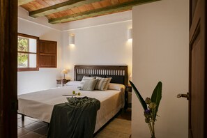 Ein Schlafzimmer mit Bett, Nachttischen, einem Fenster und einer Tür.