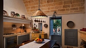 Eine Küche mit einer Steinwand, einer Pendelleuchte und einer Obstschale auf dem Tisch.