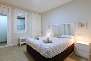 Ein Schlafzimmer mit Bett, Nachttischen, einem Kleiderschrank und einer Heizung.