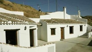 A row of white buildings with tiled roofs and small windows.