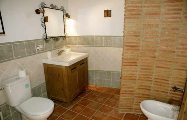 Ein Badezimmer mit Holzschrank, Waschbecken, Toilette und Duschvorhang.