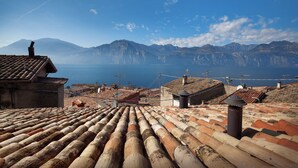 Un pueblo costero con tejados de terracota, un cielo azul despejado y vistas al mar y montañas a lo lejos.