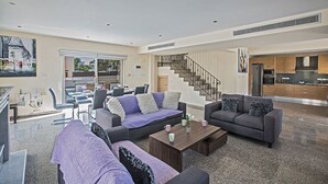 Una sala de estar amplia con un conjunto de sofás, una mesa de centro y una escalera que conduce al piso superior.