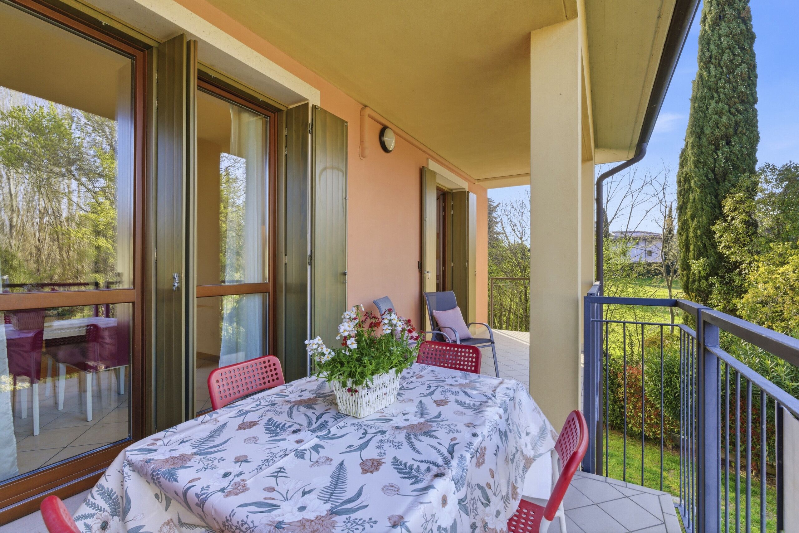 A balcony with a table, chairs, and a potted plant.
