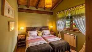 A double bed with two bedside tables, a wooden ceiling, and a window with curtains. - Rural house (full rental) "Casucas La Guariza" for 6 people (Hermandad de Campoo de Suso)