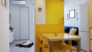 Una cocina moderna con una pared de acento amarilla, una mesa de comedor con cuatro sillas y un refrigerador.