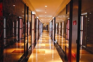 A long, well-lit hallway with reflective floors and glass doors on both sides. - Taitan International Hotel (Xinchang)