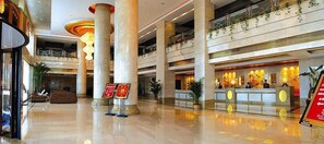 A spacious lobby with high ceilings, large columns, and a reception desk. - Taitan International Hotel (Xinchang)