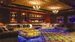 A bar area with seating, a patterned carpet, and a chandelier. - Taitan International Hotel (Xinchang)