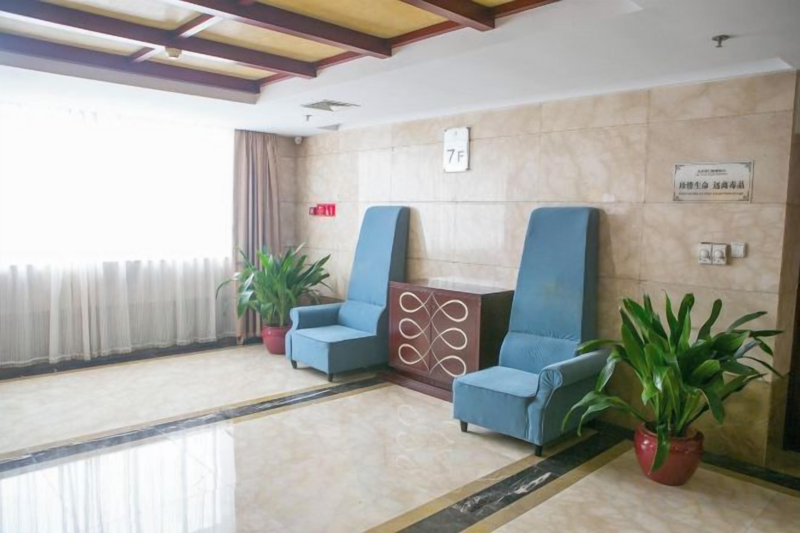 A lobby with two blue chairs, a potted plant, and a sign indicating room number 7F.