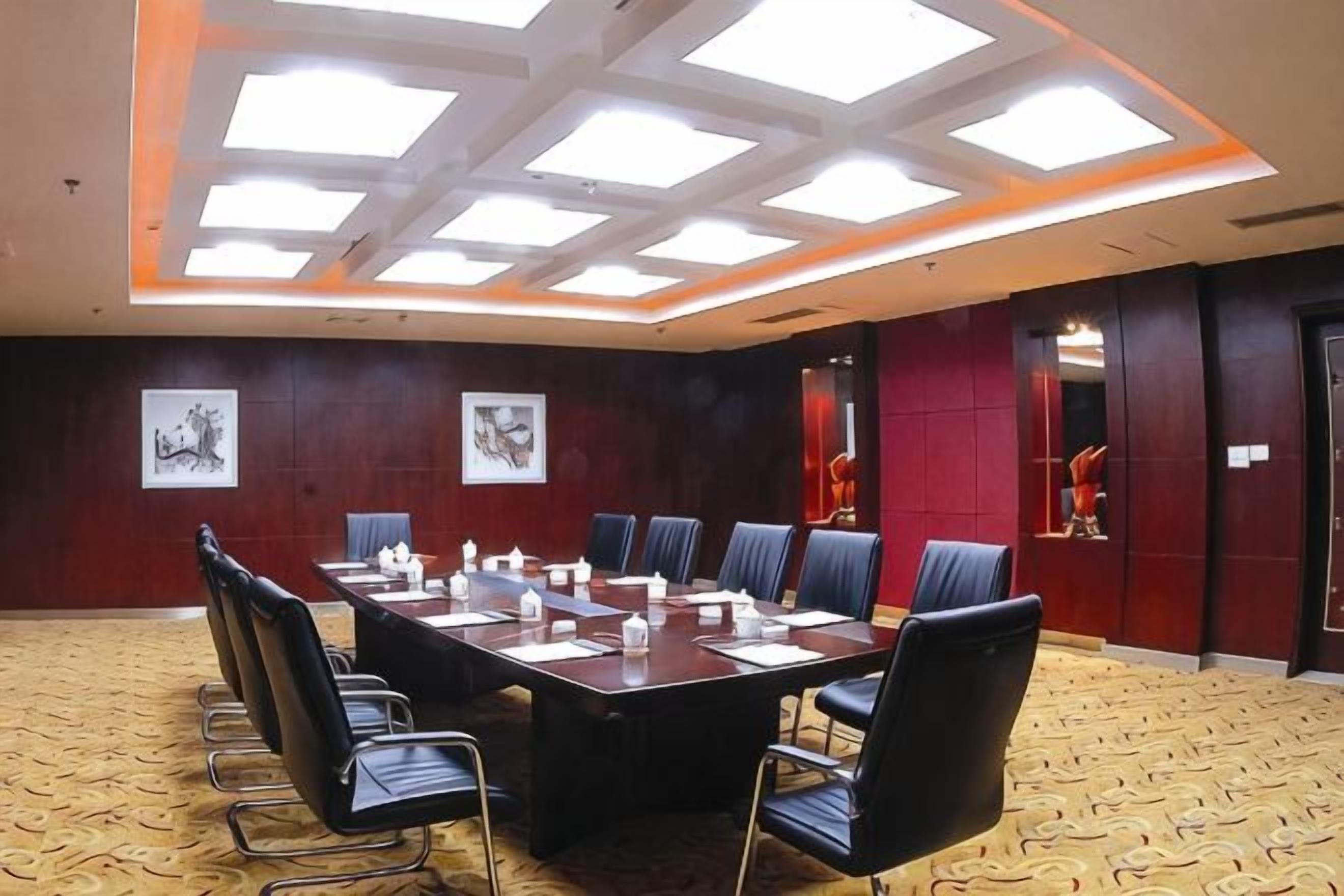A conference room with a rectangular table, chairs, and artwork on the walls.