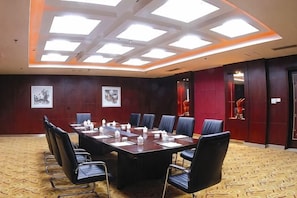 A conference room with a rectangular table, chairs, and artwork on the walls. - Taitan International Hotel (Xinchang)