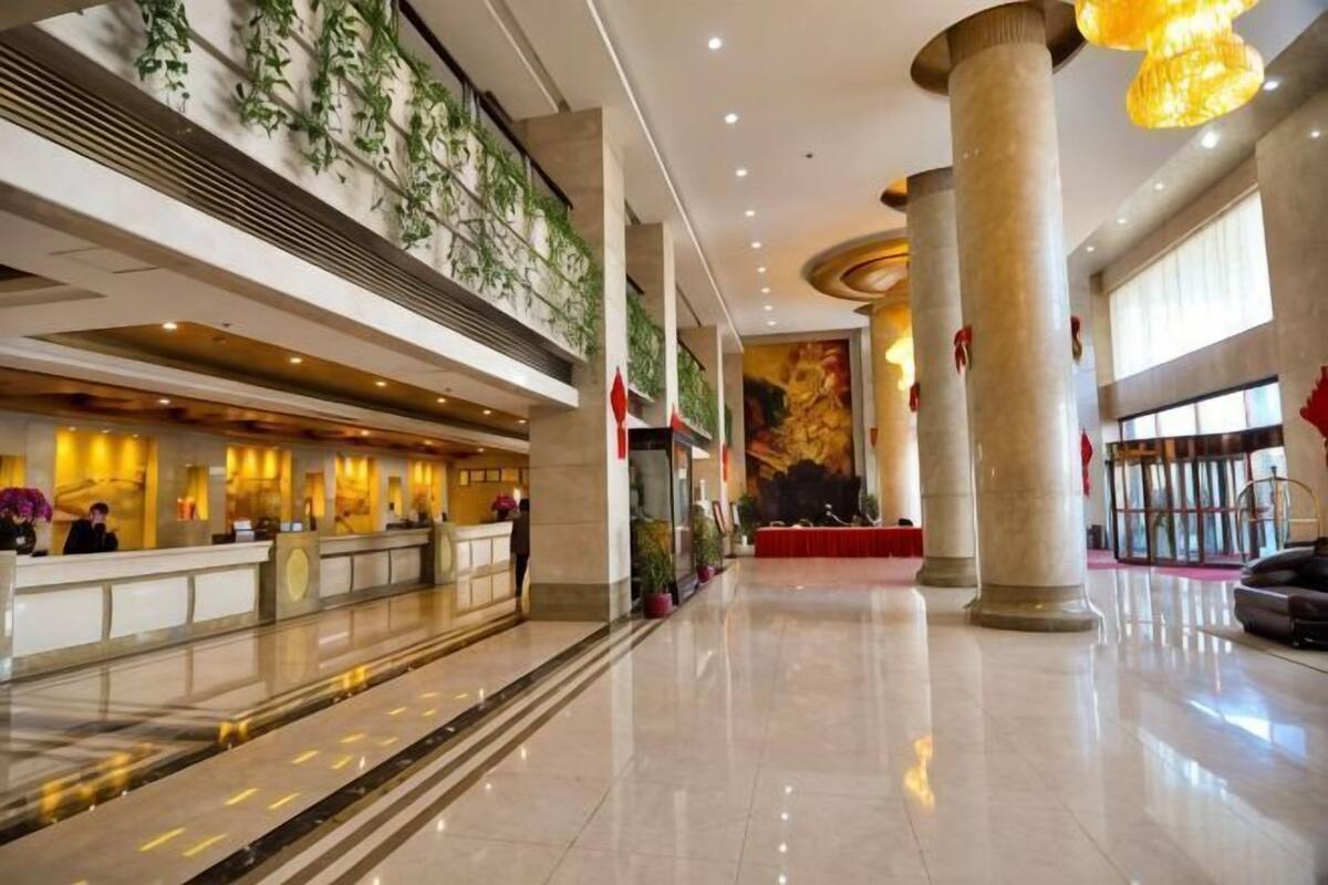 A hotel lobby with a reception desk, large columns, and a high ceiling.