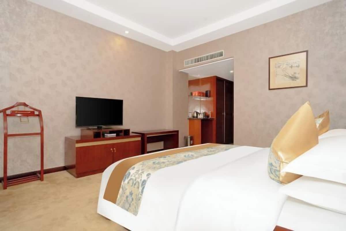 A hotel room with a bed, a television, a desk, and a wardrobe.