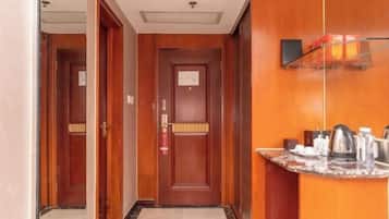 Ein Hotelgang mit Holztüren, einem Empfangstresen mit Marmorplatte und einer kleinen Küchenzeile.